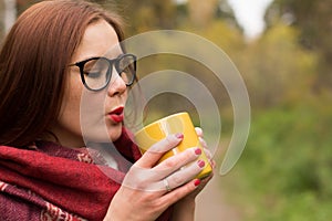 Young woman drinks hot tea from a mug to keep warm