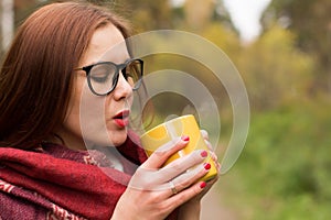 Young woman drinks hot tea from a mug to keep warm