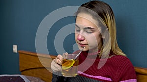 Young woman drinks tea with lemon. The girl is sick lying on the bed. Paper scarves scattered around