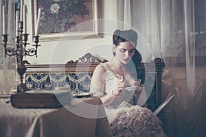 Young woman drinks tea and reads a book in a vintage interior.