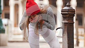 A young woman drinks water from a street fountain