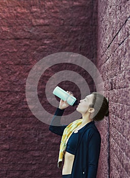 Young woman drinks water after training