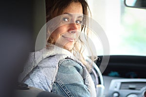 Young woman driver beginner. Girl look back in vehicle interior. Female car driver