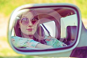 Young woman driver in the car looking to the side view mirror