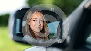 Young woman driver looking at car side view mirror