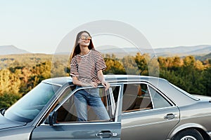 A young woman driver looks out of the car at the autumn landscape and smiles satisfactorily