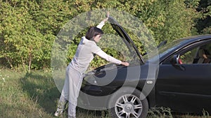 Young woman driver standing near a broken car