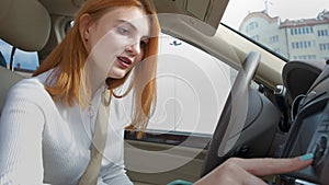 Young woman driver tuning radio behind the wheel listening to music in a car.