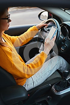 Young woman driver using mobile phone while driving car, unsafe driving