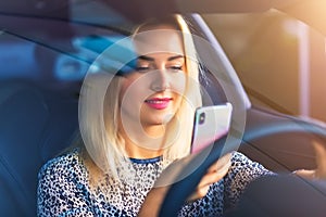 Young woman driver using a smartphone in the car