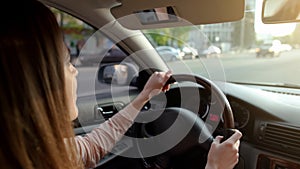 Young woman driving automobile with extended sun visor, safe transportation