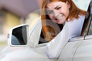 Young woman driving a car backwards. Girl with funny expression on her face while she made a fender bender damage to a rear