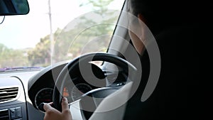 Young woman driving a car, hand put on the black steering wheel and looking forward with determination