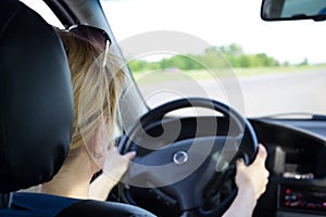 Young woman driving car on a highway. View from the back