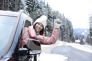 Young woman driving car and looking out of window on road.