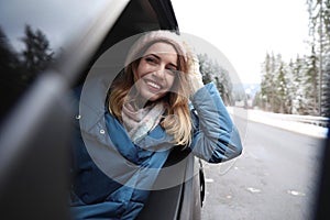 Young woman driving car and looking out of window. Winter vacation