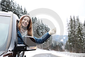 Young woman driving car and looking out of window. Winter vacation