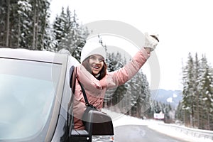 Young woman driving car and looking out of window. Winter vacation