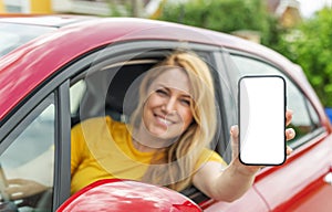 Young woman driving a car shows a smartphone screen.