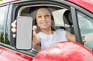 Young woman driving a car shows a smartphone screen.