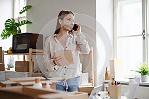 Young woman dropshipper with smartphone working at home, coronavirus concept.
