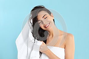 Young woman drying hair with towel on blue background photo