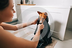 Young woman drying her dog with towel after bathing