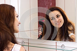 Young woman drying her hair in bathroom