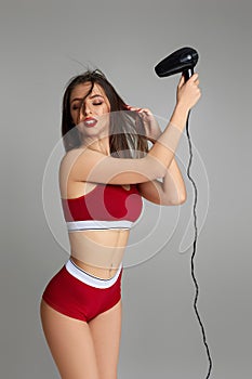 Young woman drying her hair with dryer