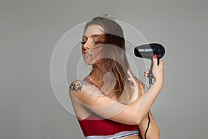 Young woman drying her hair with dryer