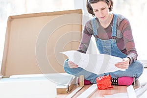 Young woman in dungarees reading instructions