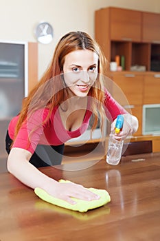 Young woman dusting wooden table