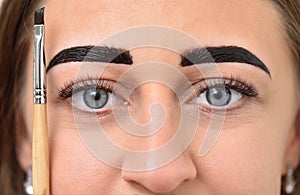 Young woman dyed her eyebrows with henna and holds a brush next to her face