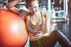 Young woman with earphones listening to music after hard workout