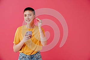 Young woman in earphones smiling and using mobile phone