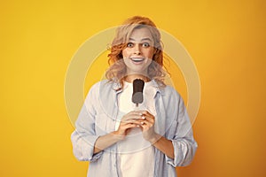 Young woman eat ice creams with chocolate glaze on yellow background. Funny redhead woman with ice cream. Amazed