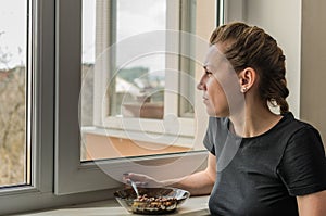 Young woman eat near the window a dry breakfast with yogurt