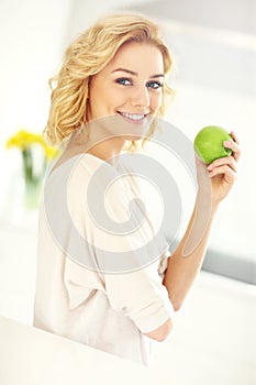 Young woman eating apple in the kitchen