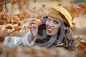 Young woman eating apple outdoor in autumn