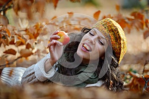 Young woman eating apple outdoor in autumn