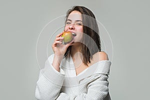Young woman eating apple over grey isolated background. Girl eat apple. Dieting or dental health care, stomatology