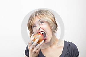Young woman eating apple on white background