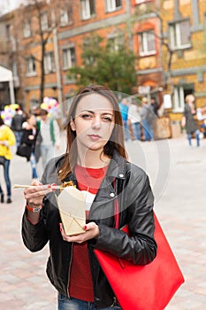 Young Woman Eating Asian Take Out at Busy Festival