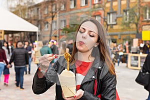 Young Woman Eating Asian Take Out at Busy Festival