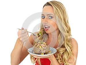 Young Woman Eating a Baked Potato with Tuna and Sweetcorn