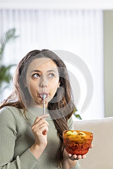 Young woman eating breakfast cereals of bowl