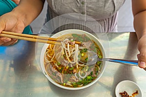 Young woman eating Bun Bo Hue, popular and delicious Vietnamese food