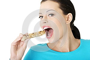 Young woman eating Cereal candy bar