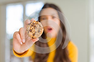 Young woman eating chocolate chips cookies at home scared in shock with a surprise face, afraid and excited with fear expression