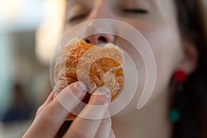 Young woman eating croissant, pleasure, guilt free eating photo
